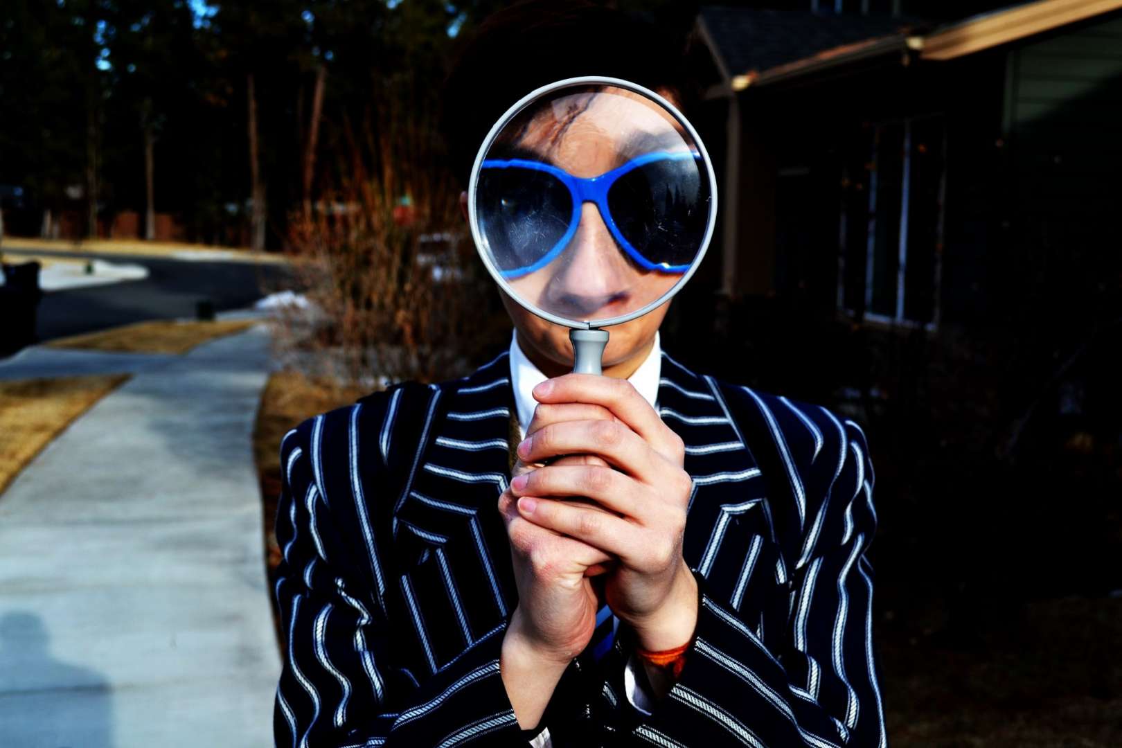 Man In Suit and Sunglasses Looking Through a Magnifying Glass